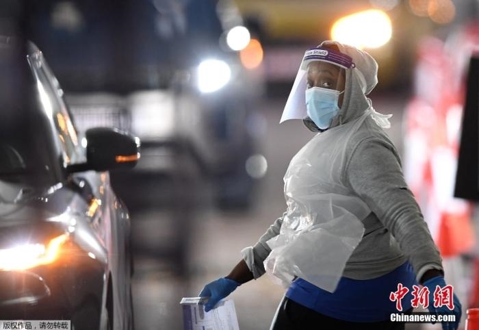 當地時間12月18日，英國政府公布的數據顯示，當天英國新增奧密克戎毒株感染病例10059例。鑒于奧密克戎毒株感染病例激增，住院人數不斷上升，倫敦市長宣布倫敦進入“重大事故”狀態(tài)。圖為倫敦的一個免下車檢測中心，一名醫(yī)務工作者正準備對司機進行核酸檢測。