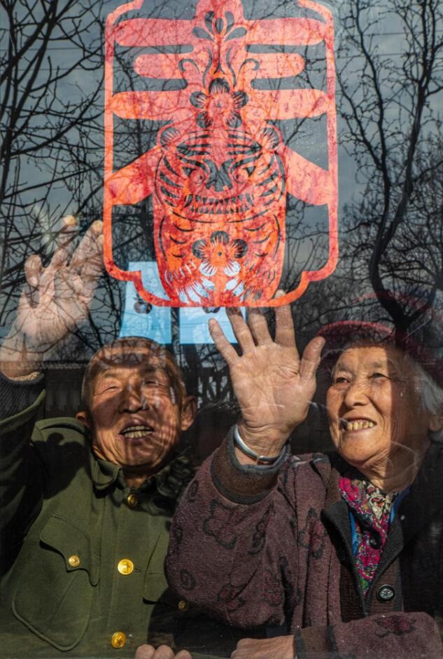 臘月里，霍州市師莊鄉(xiāng)馮南垣村村民師榮光(左)在災(zāi)后重建的新家里貼窗花。(霍州市委宣傳部供圖)