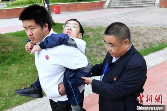 朱金祥背著鐘華強去教室上課的路上，也經(jīng)常碰到值班的校領(lǐng)導(dǎo)和老師前來搭把手。 卓忠偉 攝