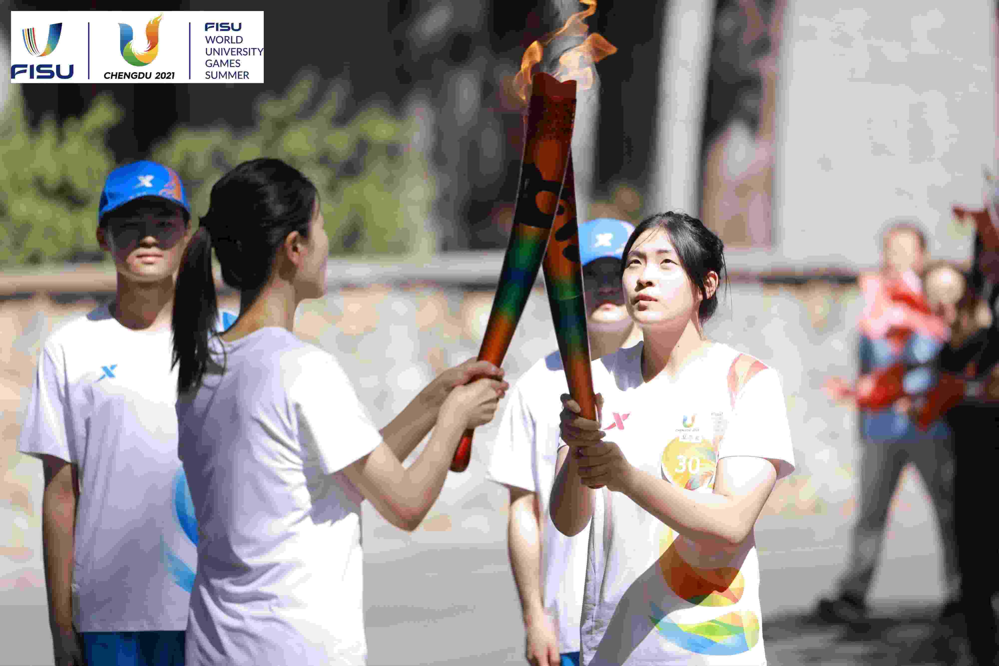 兩名大運會火炬手進行火炬?zhèn)鬟f。 圖片來源：成都大運會執(zhí)委會供圖