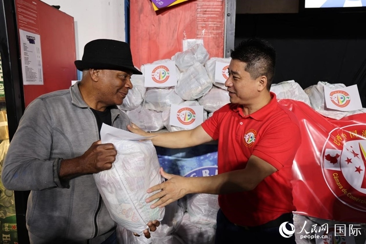 巴西中國浙江商會會長鄭俠茂向社區(qū)居民轉(zhuǎn)交捐贈物資。人民網(wǎng)記者 時元皓攝