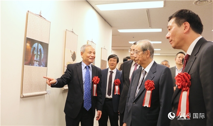 “湖州印象”攝影展主創(chuàng)、世界華人攝影協(xié)會副會長馮學敏向吳江浩大使、福田康夫前首相等嘉賓介紹展出作品。（人民網(wǎng) 許可攝）