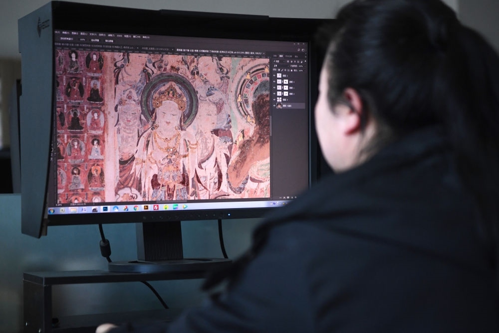 敦煌研究院文物數(shù)字化保護(hù)團(tuán)隊(duì)圖像處理人員年海麗在拼接壁畫(huà)圖像（2023年4月25日攝）。數(shù)字化探索為莫高窟的保護(hù)與傳承開(kāi)辟了全新路徑，數(shù)字技術(shù)讓敦煌文物走出洞窟，跨出國(guó)門(mén)，走向“永久保存、永續(xù)利用”。新華社記者 陳斌 攝