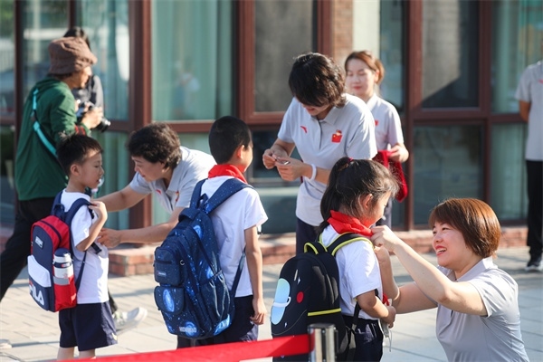 8月30日，雄安史家胡同小學(xué)學(xué)生體驗(yàn)學(xué)校生活。老師為學(xué)生佩戴校徽。