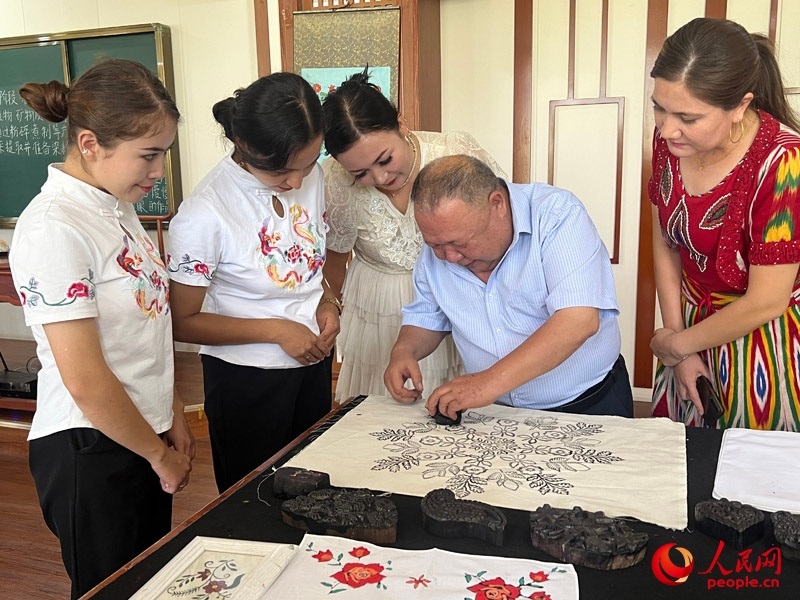 國家級非物質文化遺產(chǎn)模戳印花布技藝傳承人吾吉阿西木?吾舒爾展示模戳印花布的制作過程。人民網(wǎng)記者 常雪梅攝