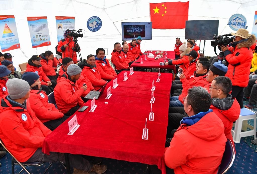 海拔4950米的卓奧友峰科考大本營，科考隊員趙華標(biāo)（手拿麥克風(fēng)看電腦者）在宣讀剛剛接收到的頂峰氣象觀測數(shù)據(jù)，這標(biāo)志著峰頂自動氣象站架設(shè)成功，成功傳回觀測數(shù)據(jù)（10月1日攝）。新華社記者晉美多吉 攝
