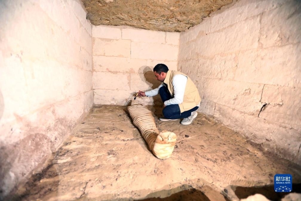 10月15日，在埃及明亞省考古現(xiàn)場，考古人員清理一座石鑿墓中的木乃伊。新華社發(fā)（艾哈邁德·戈馬攝）