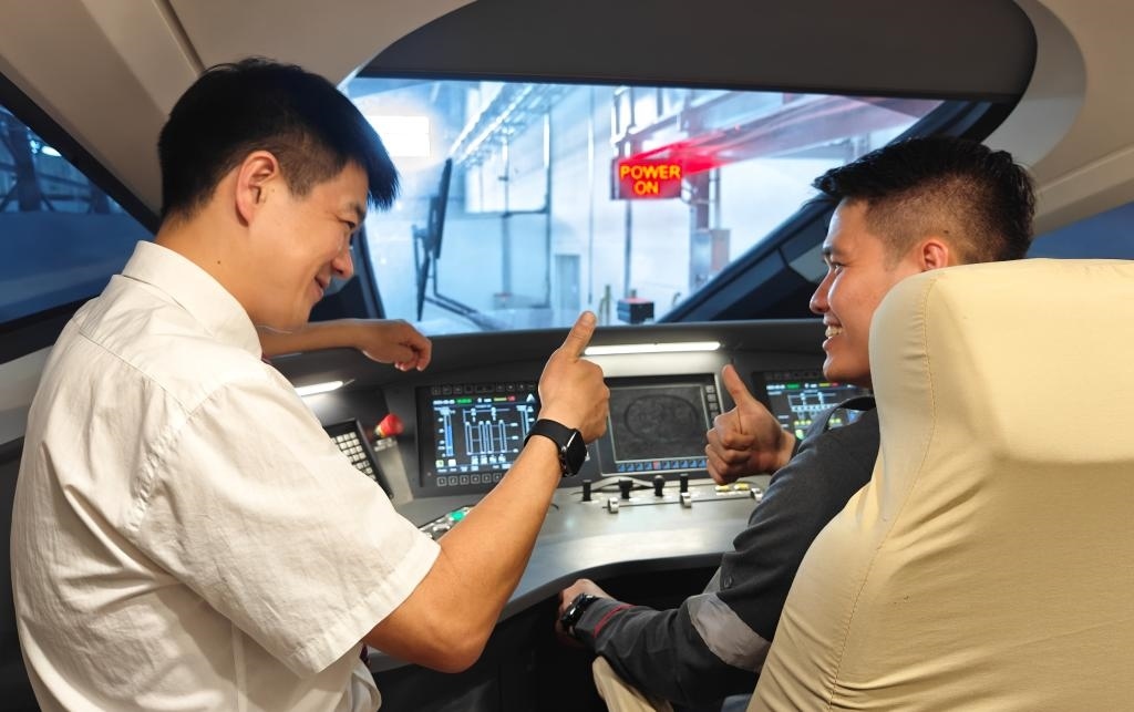 8月25日，在印度尼西亞萬隆的雅萬高鐵德卡魯爾動(dòng)車所內(nèi)，中國(guó)師傅穆振（左）在向印尼火車司機(jī)塞蒂亞萬講解動(dòng)車組出庫前的上電作業(yè)。