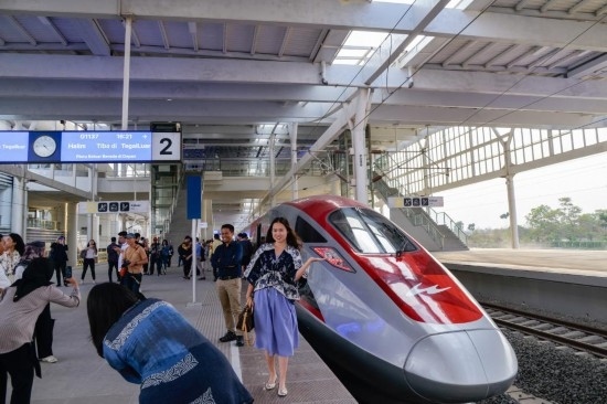  10月17日，在印度尼西亞萬隆德卡魯爾站，乘客在站臺上和雅萬高鐵高速動車組列車合影。新華社記者 徐欽 攝