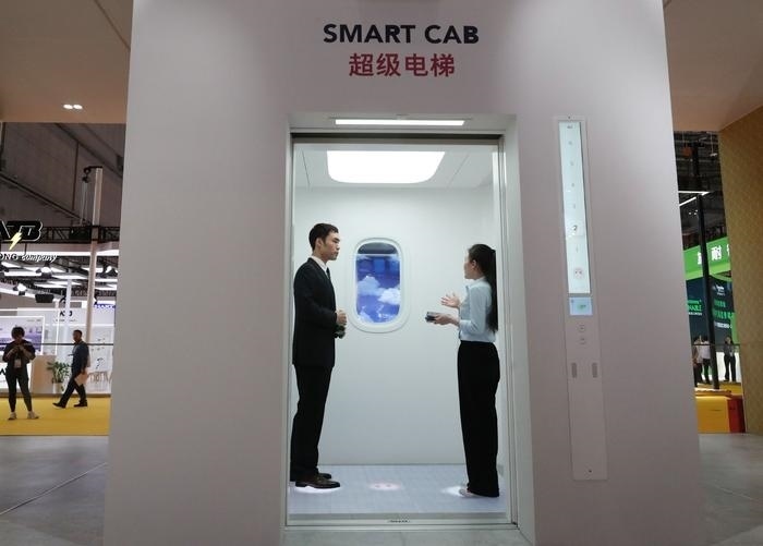 11月5日，工作人員（右）在第六屆進(jìn)博會上向參觀者介紹奧的斯公司全新推出的超級電梯。