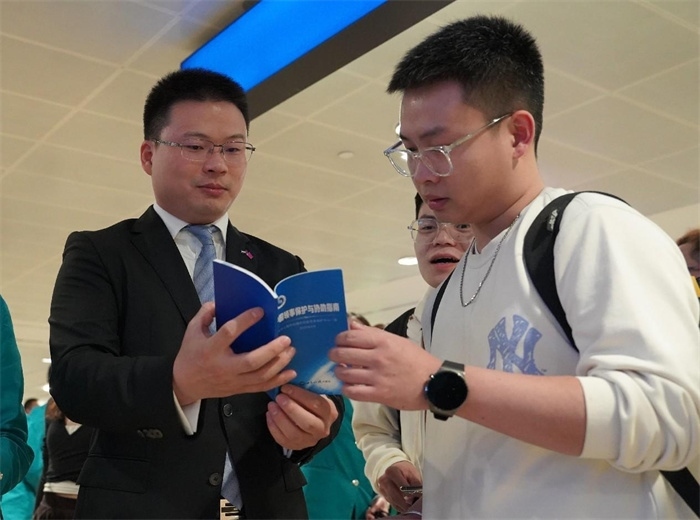 工作人員（左一）在發(fā)放《中國領事保護與協(xié)助指南》。 中國駐迪拜總領事館供圖