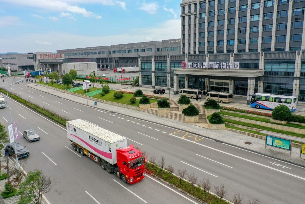 2023年10月11日，滿載筆記本電腦配件、發(fā)電機(jī)組件等產(chǎn)品的西部陸海新通道跨境公路班車從重慶南彭公路保稅物流中心駛出，將途經(jīng)廣西憑祥，直達(dá)越南（無人機(jī)照片）。新華社記者 黃偉 攝