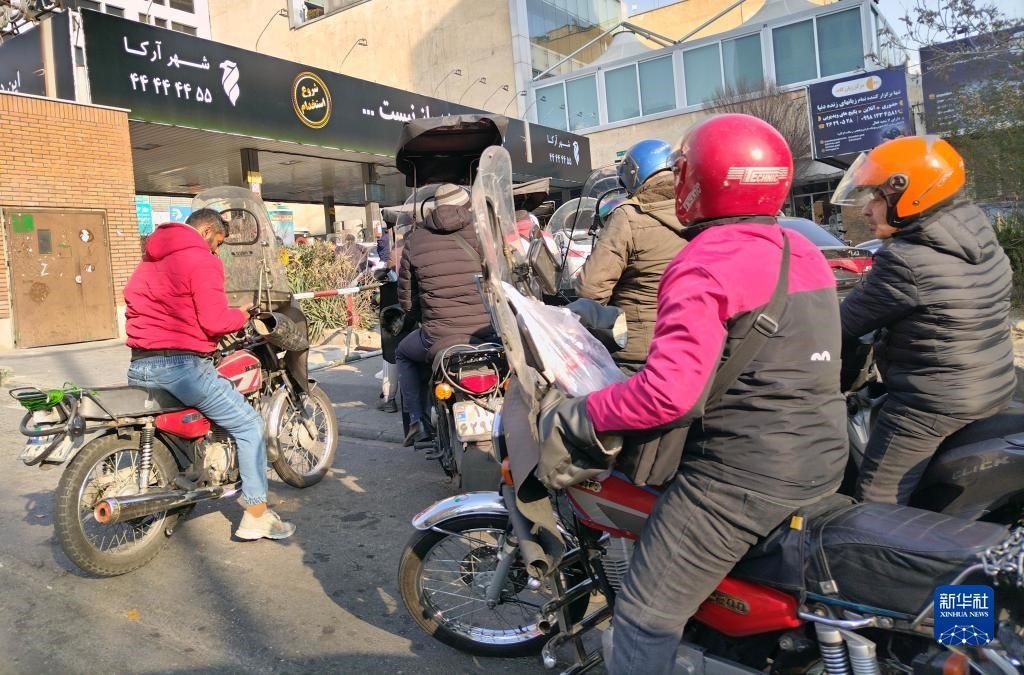 12月18日，摩托車在伊朗首都德黑蘭的一家加油站外等待加油。新華社記者 沙達提 攝