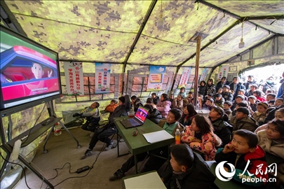 12月22日，在積石山縣大河家鎮(zhèn)大河村安置點(diǎn)，陸軍76集團(tuán)軍某旅搭建的“臨時(shí)學(xué)校”內(nèi)，小朋友正在看動(dòng)畫(huà)片。人民網(wǎng)記者 翁奇羽攝