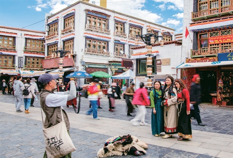 千年八廓街，見證民族團(tuán)結(jié)。2021年7月，習(xí)近平總書記來到位于西藏拉薩老城區(qū)的八廓街，感慨地說：“千年八廓街，是我們各民族建起來的八廓街。各民族文化在這里交流交往交融，我們中華民族的大家庭在這里其樂融融?！眻D為2023年6月13日，游客身著藏裝在八廓街拍照留念。 新華社記者 姜帆/攝