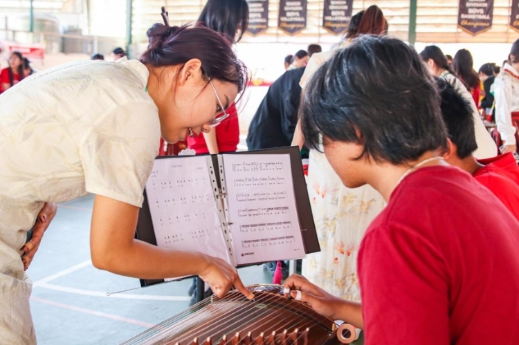 志愿者教師指導(dǎo)學(xué)生彈奏古箏。活動(dòng)主辦方供圖