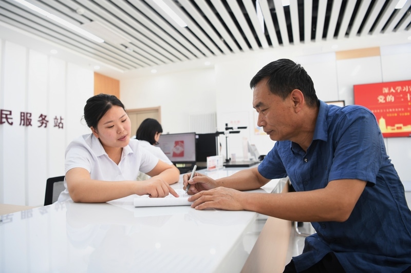 2023年5月23日，河北雄安新區(qū)容東片區(qū)南文營社區(qū)居民（右）在社區(qū)便民服務(wù)站辦理業(yè)務(wù)。