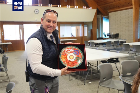 △馬斯卡廷中學(xué)高中部校長(zhǎng)瑞安·卡斯?fàn)柎韺W(xué)校接受總臺(tái)文創(chuàng)產(chǎn)品