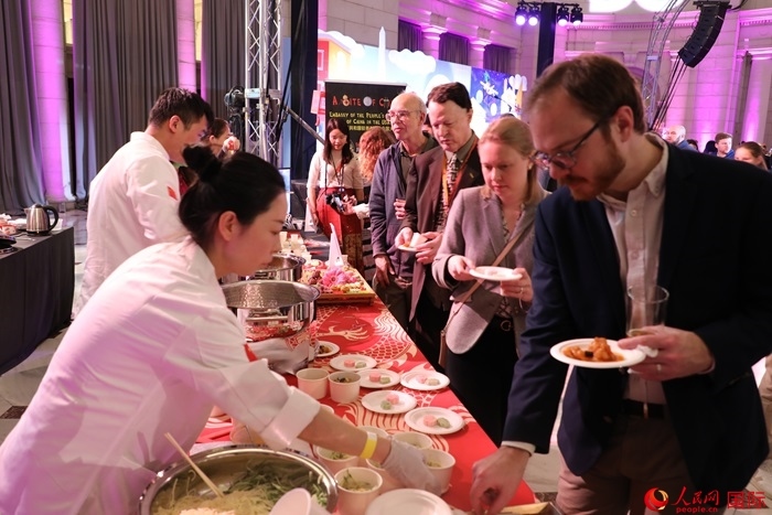 當(dāng)?shù)貢r(shí)間3月7日晚，華盛頓聯(lián)合車站廣場(chǎng)舉行駐美使團(tuán)“使館主廚挑戰(zhàn)賽”。圖為當(dāng)?shù)孛癖娫谥袊古_(tái)前體驗(yàn)中國美食。人民網(wǎng)記者 李志偉攝