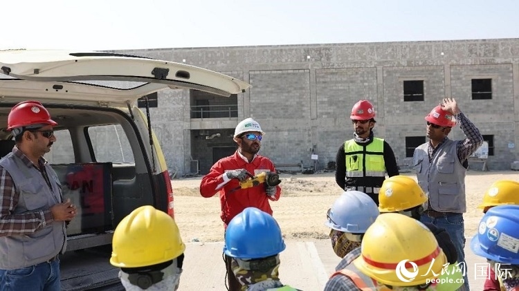 穆薩瓦爾(圖中紅衣人）現(xiàn)場(chǎng)演示工具操作規(guī)范。人民網(wǎng)記者 管克江攝