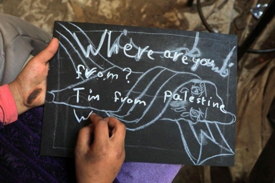 2023年12月28日，一名學(xué)生在加沙地帶南部城市拉法一所學(xué)校的臨時(shí)教室中寫下“我來自巴勒斯坦”的字樣。新華社發(fā)（里澤克·阿卜杜勒賈瓦德攝）