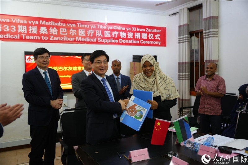 江蘇省蘇北人民醫(yī)院黨委書記束余聲與桑衛(wèi)生部首席秘書哈比巴交換捐贈(zèng)書。中國(guó)援桑醫(yī)療隊(duì)供圖