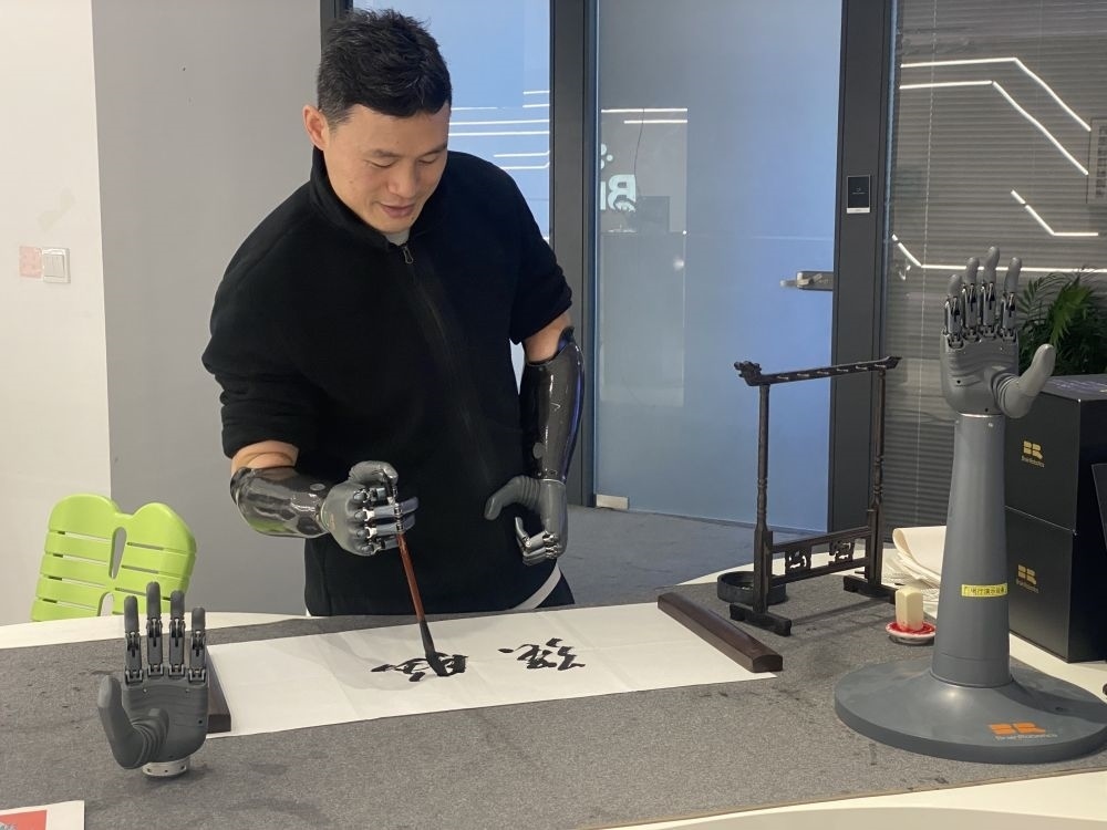 2024年3月29日，在浙江強腦科技有限公司展廳內(nèi)，失去雙手的產(chǎn)品體驗官倪敏成依靠智能仿生手寫毛筆字。新華社記者 魏一駿 攝