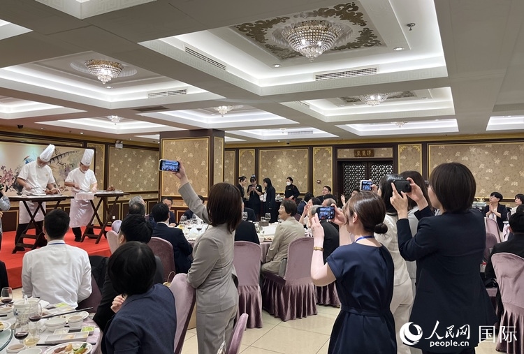 國家級(jí)非物質(zhì)文化遺產(chǎn)、全聚德片鴨工藝吸引代表團(tuán)成員拍照留念。