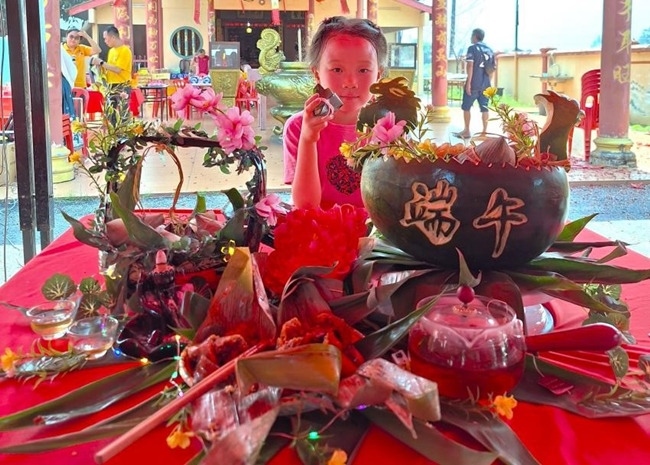 小朋友展示學(xué)裹粽子的成品照。組委會供圖