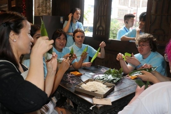 6月9日，美國青年代表在重慶永川松溉古鎮(zhèn)體驗包粽子。新華社記者 周思宇 攝