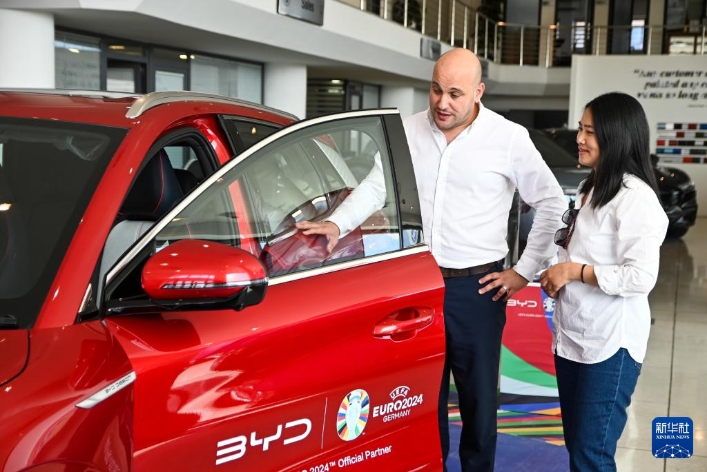 2024年5月29日，在馬耳他比爾基卡拉，馬耳他哈桑-扎米特汽車公司首席執(zhí)行官德古阿拉（左）介紹一輛比亞迪純電動汽車。新華社發(fā)（喬納森·博格 攝）