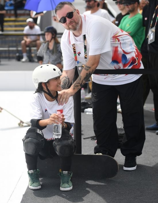 6月20日，鄭好好（左）在比賽間隙與教練互動，她在預賽中最佳成績?yōu)?2.60分。當日，巴黎奧運會資格系列賽布達佩斯站滑板女子碗池預賽在布達佩斯舉行。新華社記者 賀燦鈴 攝