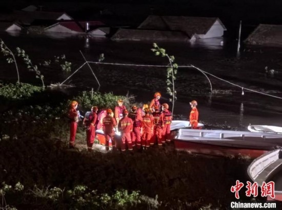  7月6日凌晨3時(shí)，在湖南岳陽(yáng)華容縣團(tuán)洲垸洞庭湖一線堤防，救援人員剛剛完成一次救援任務(wù)，遠(yuǎn)處是被淹的民房。中新社記者 白祖偕 攝