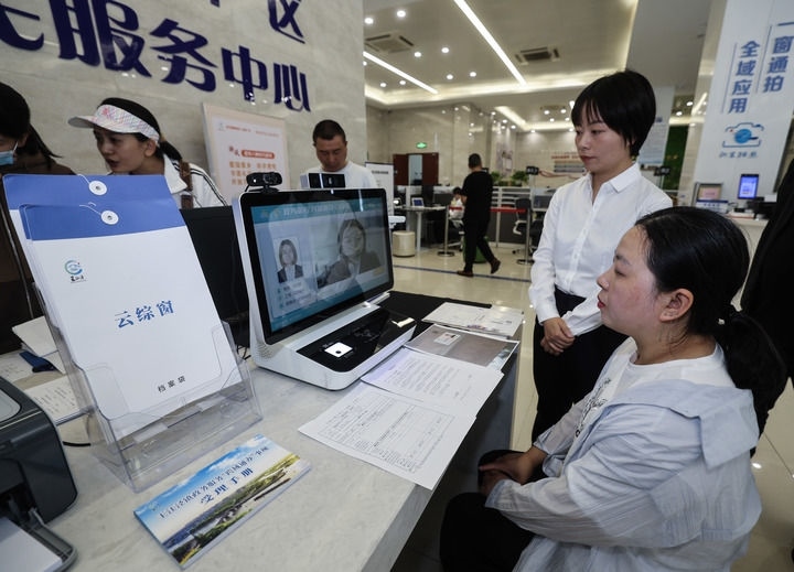 在浙江省嘉興市秀洲區(qū)王江涇鎮(zhèn)便民服務(wù)中心的“跨域通辦·云綜窗”窗口，辦理開業(yè)登記的個體工商戶（右一）通過該系統(tǒng)與江蘇省蘇州市吳江區(qū)盛澤鎮(zhèn)行政審批局工作人員視頻連線，進(jìn)行身份讀取及材料線上審核（2024年5月9日攝）。新華社記者 徐昱 攝