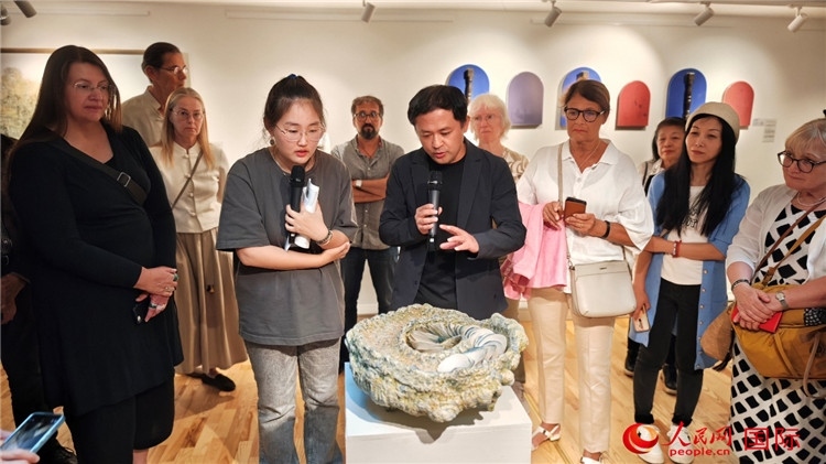 參展人、景德鎮(zhèn)陶瓷大學(xué)設(shè)計(jì)藝術(shù)學(xué)院副院長(zhǎng)余劍峰（中）向來(lái)賓介紹參展作品。人民網(wǎng)記者 殷淼攝
