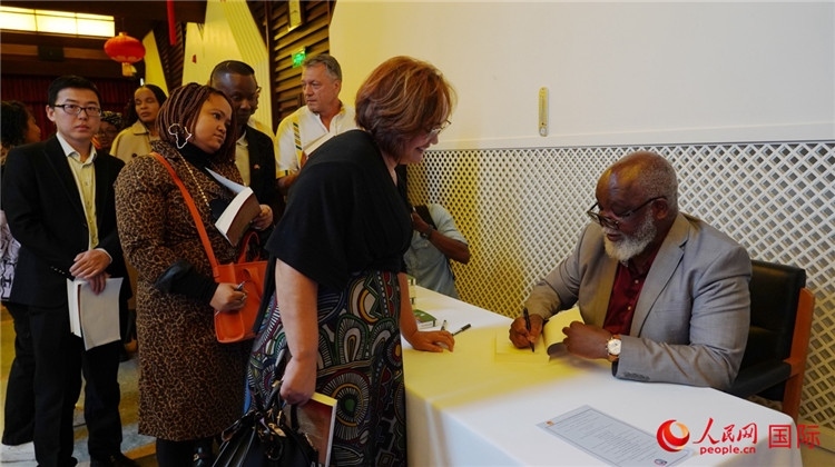 譚哲理在活動現(xiàn)場簽名贈書。人民網(wǎng) 劉暢攝