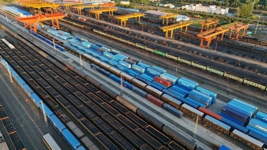 這是2024年8月14日在黑龍江綏芬河鐵路口岸集裝箱換裝場拍攝的集裝箱換裝作業(yè)現(xiàn)場（無人機照片）。今年前七個月，綏芬河鐵路口岸開行中歐班列573列，運量達55246標箱，同比分別增長23%和18%，班列數(shù)量持續(xù)保持高位運行。