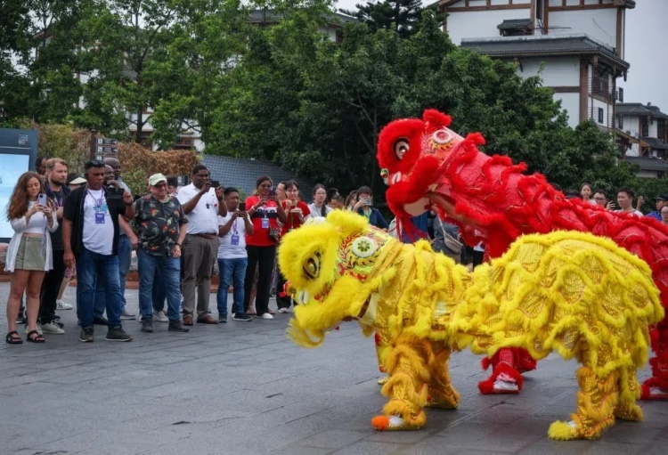 2024“一帶一路”媒體合作論壇聯(lián)合采訪調(diào)研行成員在樂山蘇稽古鎮(zhèn)觀看非遺舞獅表演。本報(bào)記者 伊霄攝