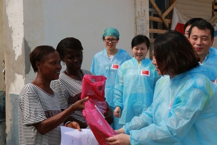 2015年4月4日，在位于塞拉利昂首都弗里敦市郊的中塞友好醫(yī)院埃博拉診療中心，中國(guó)第四批援塞醫(yī)療隊(duì)副隊(duì)長(zhǎng)邵蔚（右前）向被治愈的埃博拉出血熱患者贈(zèng)送禮物。新華社發(fā)（祖榮強(qiáng) 攝）