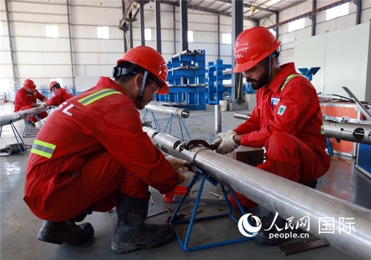 中伊員工共同在檢修鉆井設(shè)備。人民網(wǎng)記者管克江攝