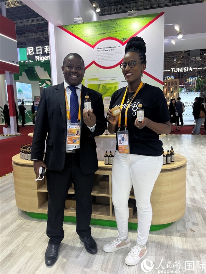 6月6日，布隆迪駐華大使館一等參贊布利馬索·阿爾弗雷德 (左，Bulimaso Alfred) 和參展商卡馬里扎·埃斯特拉 (Kamariza Estella) 在第七屆中國(guó)國(guó)際進(jìn)口博覽會(huì)布隆迪館展示當(dāng)?shù)厣a(chǎn)的辣木油。（人民網(wǎng) 艾里士 攝）
