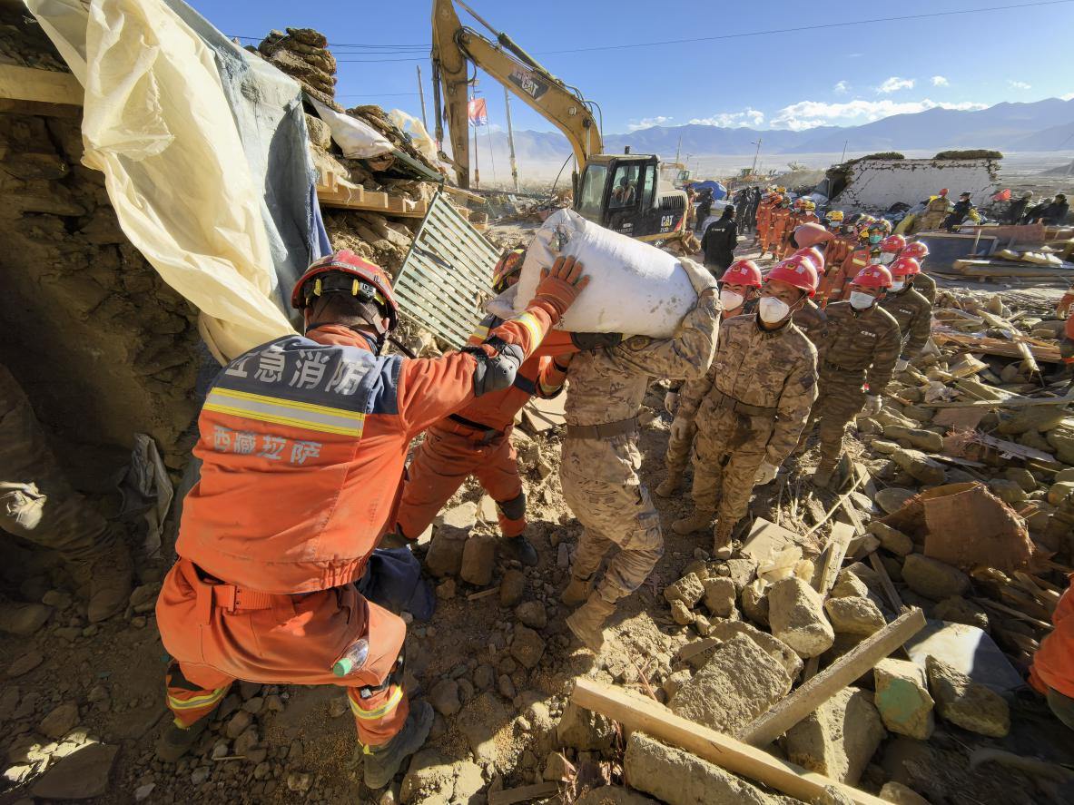 1月11日，定日縣長(zhǎng)所鄉(xiāng)古榮村，應(yīng)急消防等救援人員排隊(duì)接力搶運(yùn)掩埋在倒塌房屋下的群眾財(cái)物。人民日?qǐng)?bào)記者楊翹楚攝