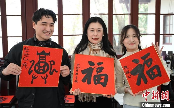1月20日，外籍留學(xué)生和西泠印社社員李硯(中)展示各自創(chuàng)作的福貼。當(dāng)日，來自巴西、馬來西亞、加納、哈薩克斯坦的外籍留學(xué)生在浙江杭州西泠印社體驗(yàn)福貼、春聯(lián)和篆刻，感受古老的中國傳統(tǒng)文化。中新社記者 王剛 攝