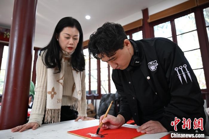 1月20日，外籍留學(xué)生在西泠印社社員李硯指導(dǎo)下寫福。當(dāng)日，來自巴西、馬來西亞、加納、哈薩克斯坦的外籍留學(xué)生在浙江杭州西泠印社體驗(yàn)福貼、春聯(lián)和篆刻，感受古老的中國傳統(tǒng)文化。中新社記者 王剛 攝