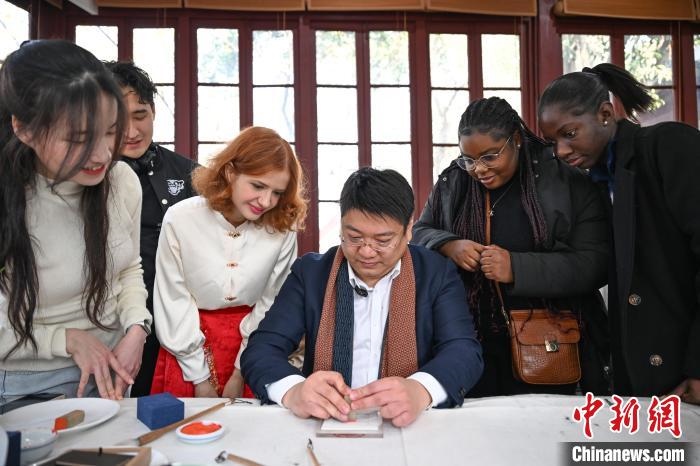 1月20日，篆刻家王臻向外籍留學(xué)生展示篆刻印章。當(dāng)日，來自巴西、馬來西亞、加納、哈薩克斯坦的外籍留學(xué)生在浙江杭州西泠印社體驗(yàn)福貼、春聯(lián)和篆刻，感受古老的中國傳統(tǒng)文化。中新社記者 王剛 攝