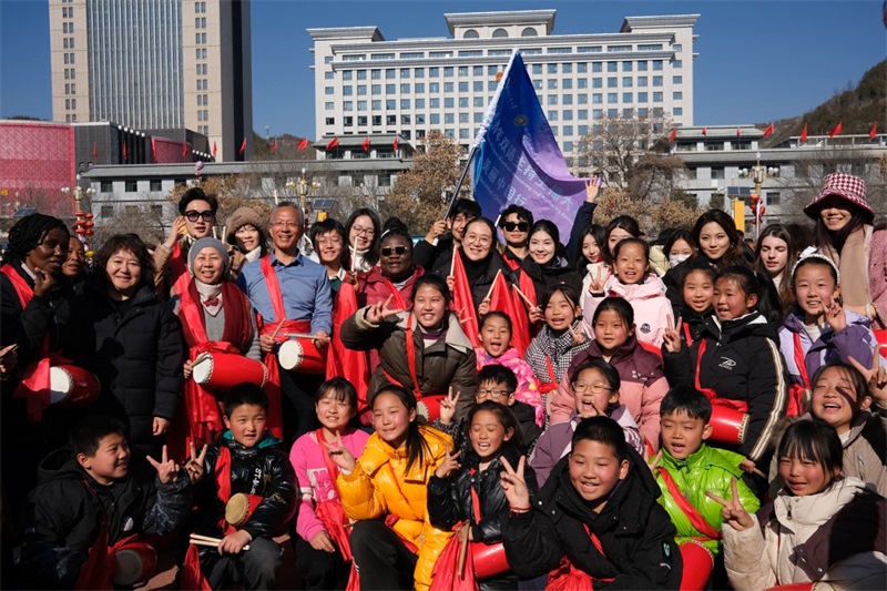 中外青年學(xué)子在安塞文化廣場觀看陜北腰鼓和大秧歌表演后合影留念，大家踏著鼓點(diǎn)共舞，翻飛的紅綢與躍動(dòng)的身影交織，在黃土地廣場上繪出一幅生動(dòng)的陜北民俗互動(dòng)畫卷