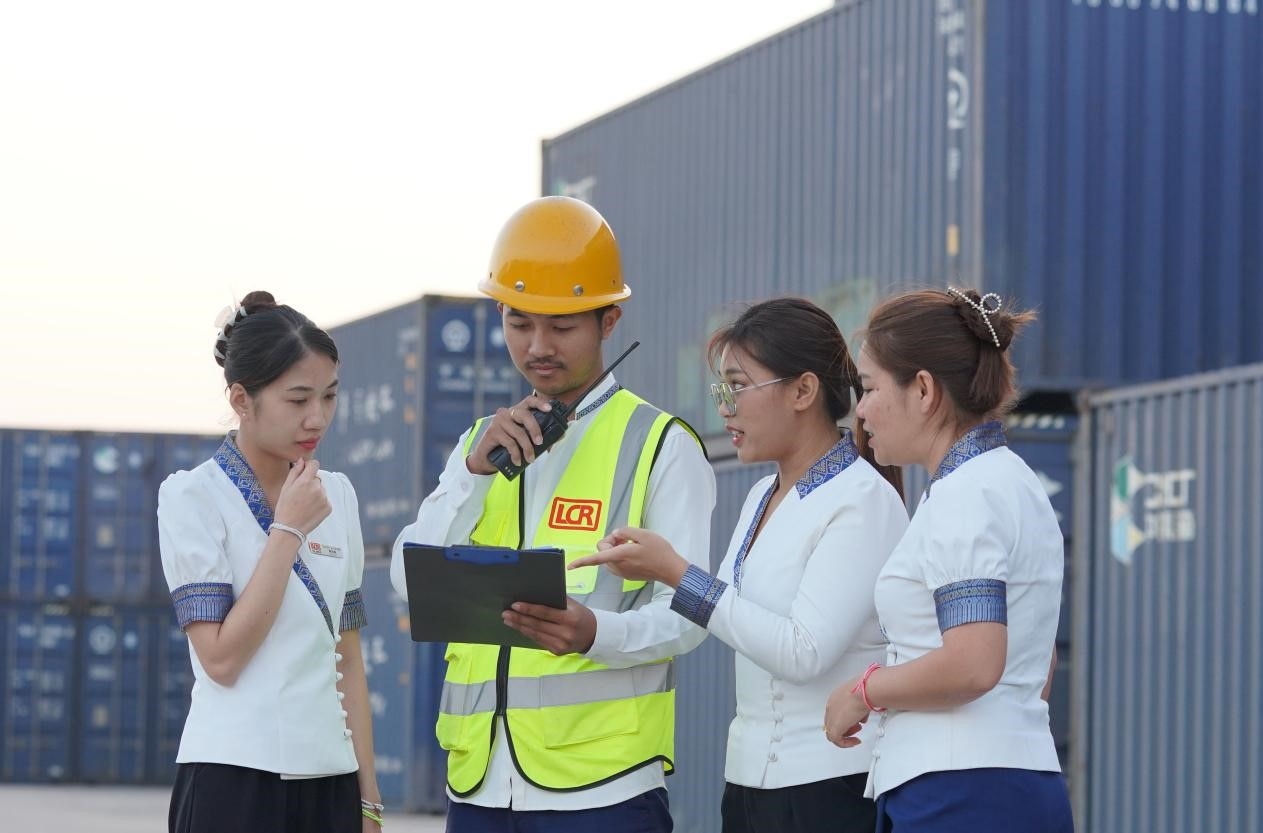 萬象南站貨運值班員陳尼啦（左一）與同事在一起討論工作。老中鐵路有限公司供圖