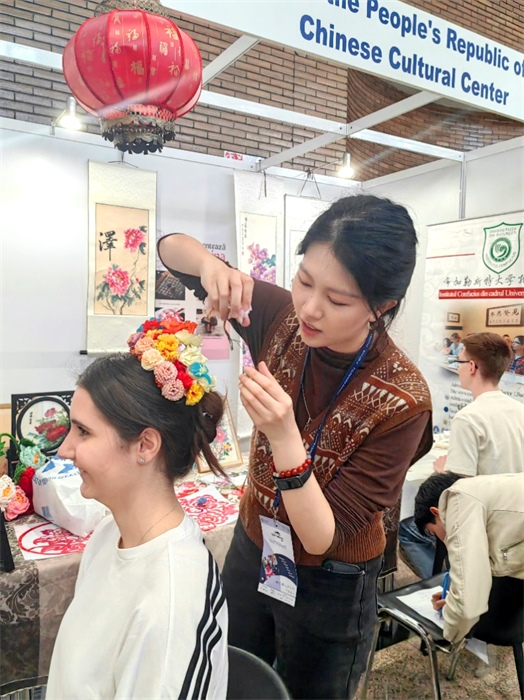 展覽正值羅馬尼亞迎春花節(jié)，國際中文教師志愿者潘婧穎向游客們介紹了國家非物質(zhì)文化遺產(chǎn)——福建泉州的簪花文化。布加勒斯特大學(xué)孔子學(xué)院供圖。