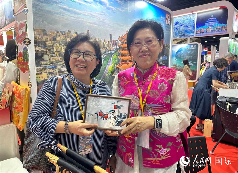 中國“大冶刺繡”傳承人劉小紅（右）參加泰國國際旅游展，向觀眾介紹中國非遺刺繡針法。人民網(wǎng)記者 簡承淵攝