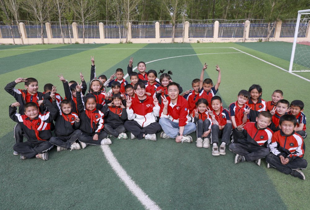 4月23日，在新疆克州阿圖什市哈拉峻鄉(xiāng)謝依特小學(xué)，支教教師王俊文（中左）、李軻凡（中右）和學(xué)生在一起。